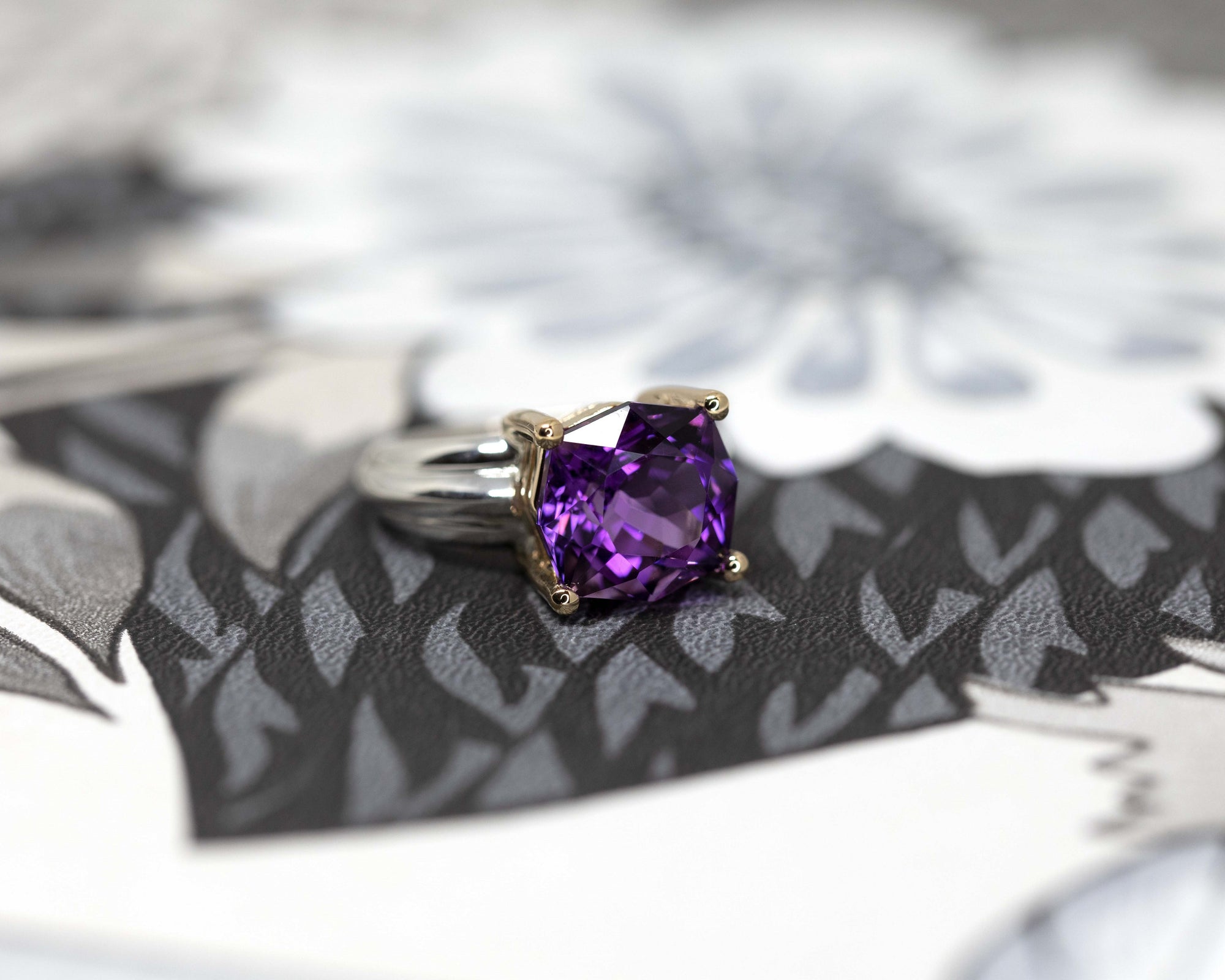 Top view on gray background: The Amethyst Cocktail Ring with its striking Brazilian amethyst and contrasting silver-gold band. A luxurious custom design by Bena Jewelry, crafted in Montreal, Canada.