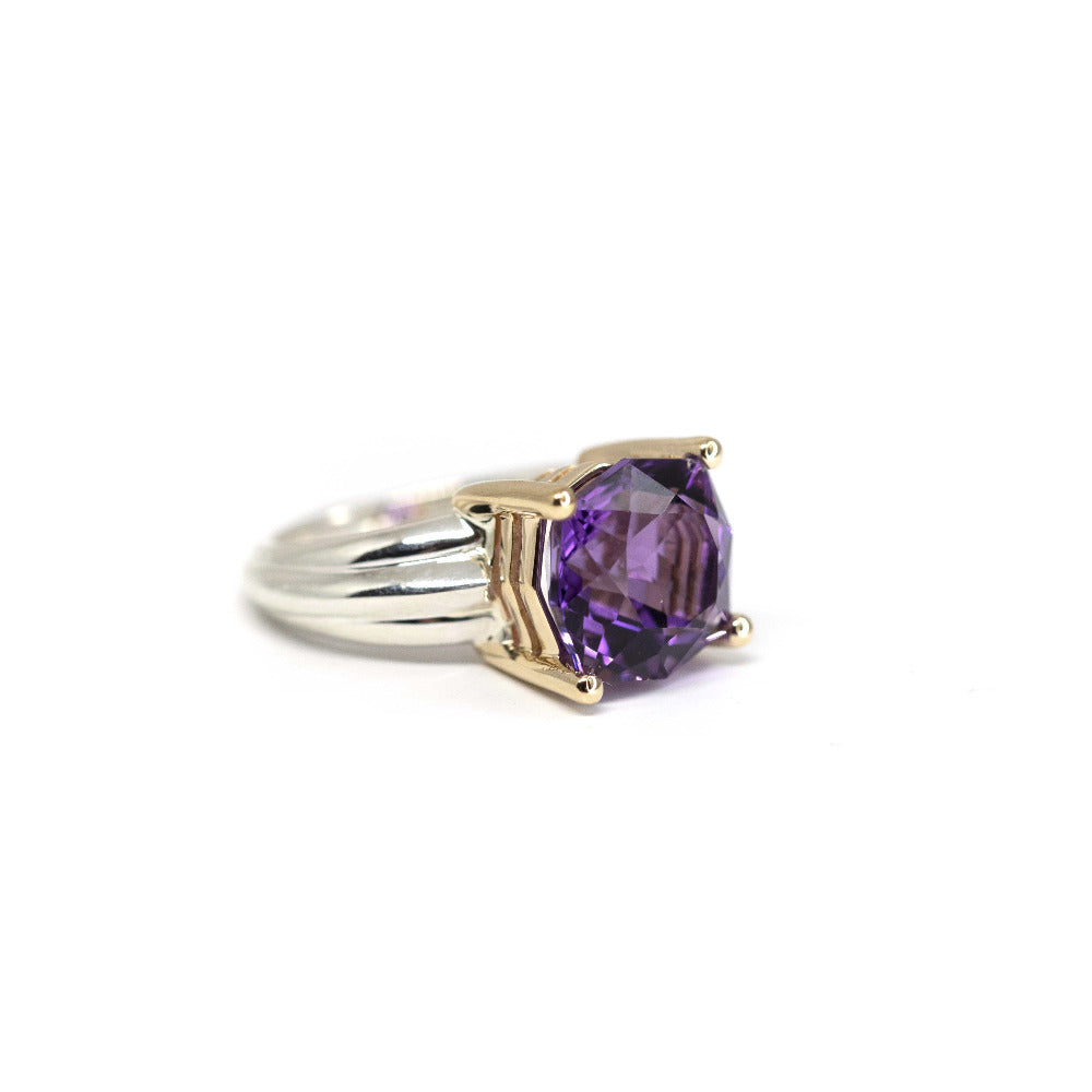 Close-up of the ring: Focus on the amethyst’s brilliance and the contrasting silver and gold elements on the hand.