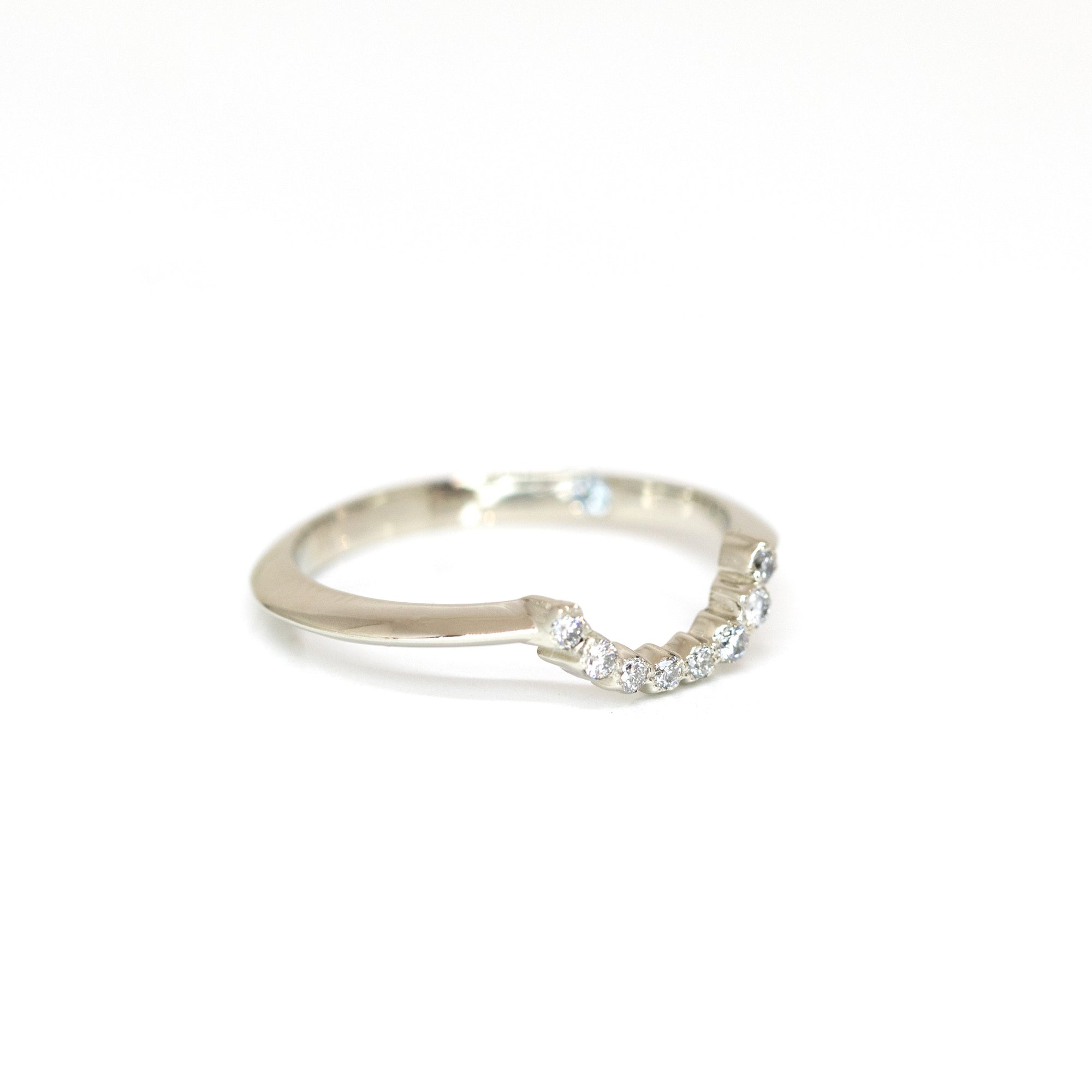 Fine white gold ring with sparkling round diamonds in a graceful curve. Handmade by Bena Jewelry, a Montreal-based designer. Photographed on a white background to highlight its refined craftsmanship.