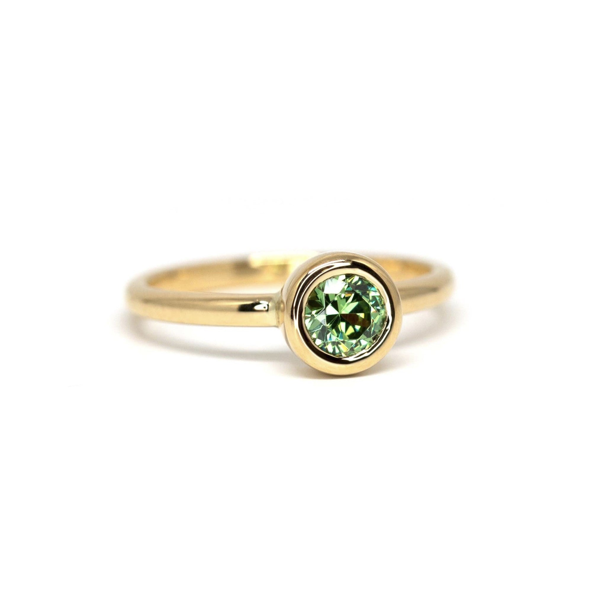 Minimalist green garnet engagement ring in yellow gold, Bezel Set Demantoide by Bena Jewelry, displayed on a clean white background. Custom-made in Montreal.