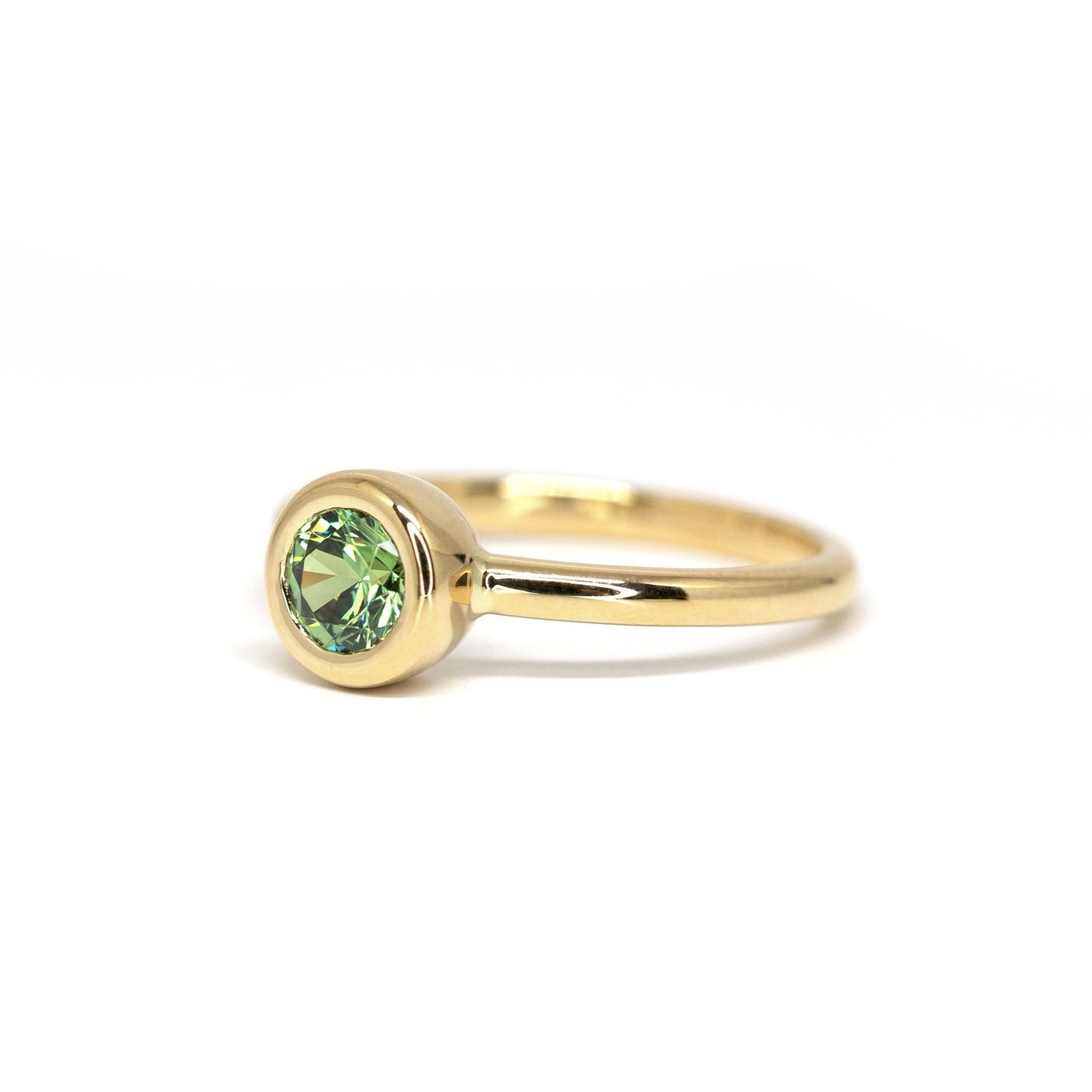 Unique green demantoid garnet ring in yellow gold by Bena Jewelry, photographed on a white background. Handmade wedding or engagement ring.