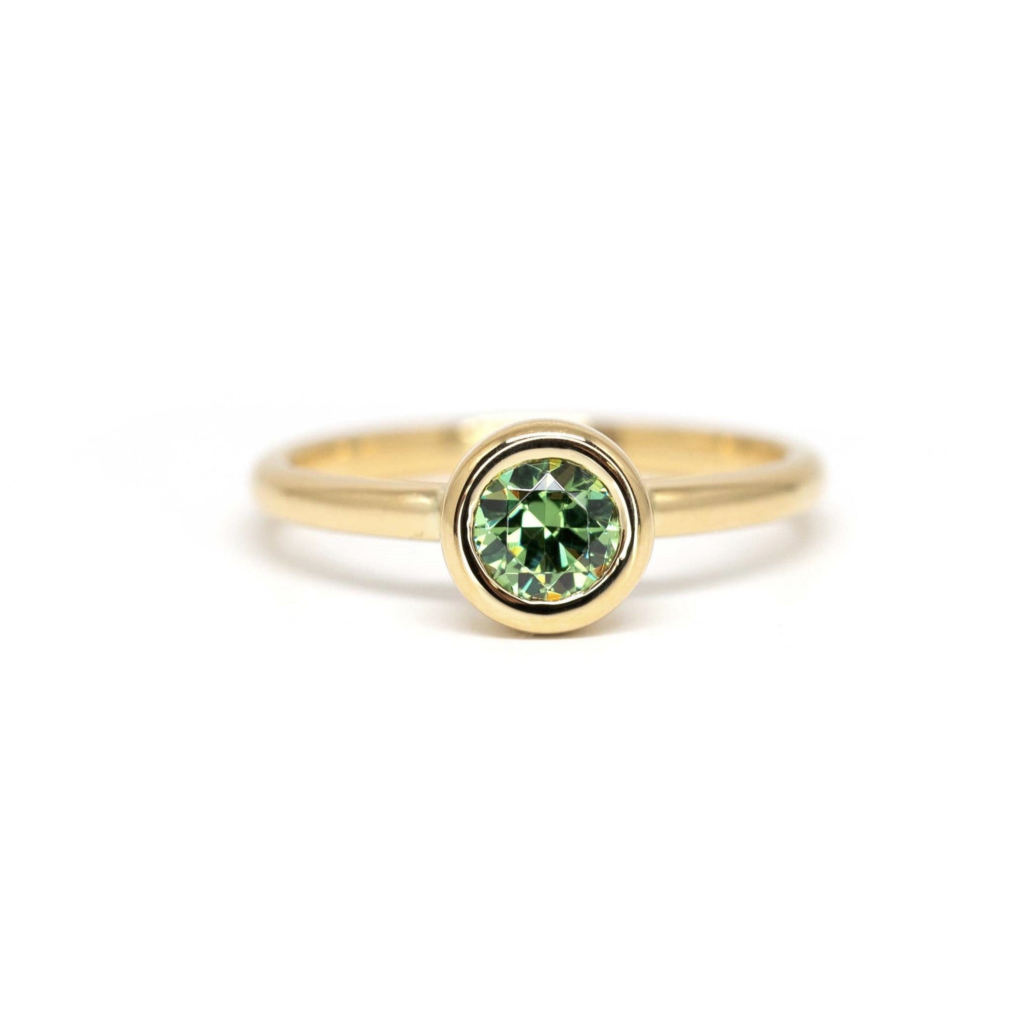 Bena Jewelry’s Bezel Set Demantoide Ring, crafted in yellow gold with a bezel-set green garnet, displayed on a white background. Made in Canada.