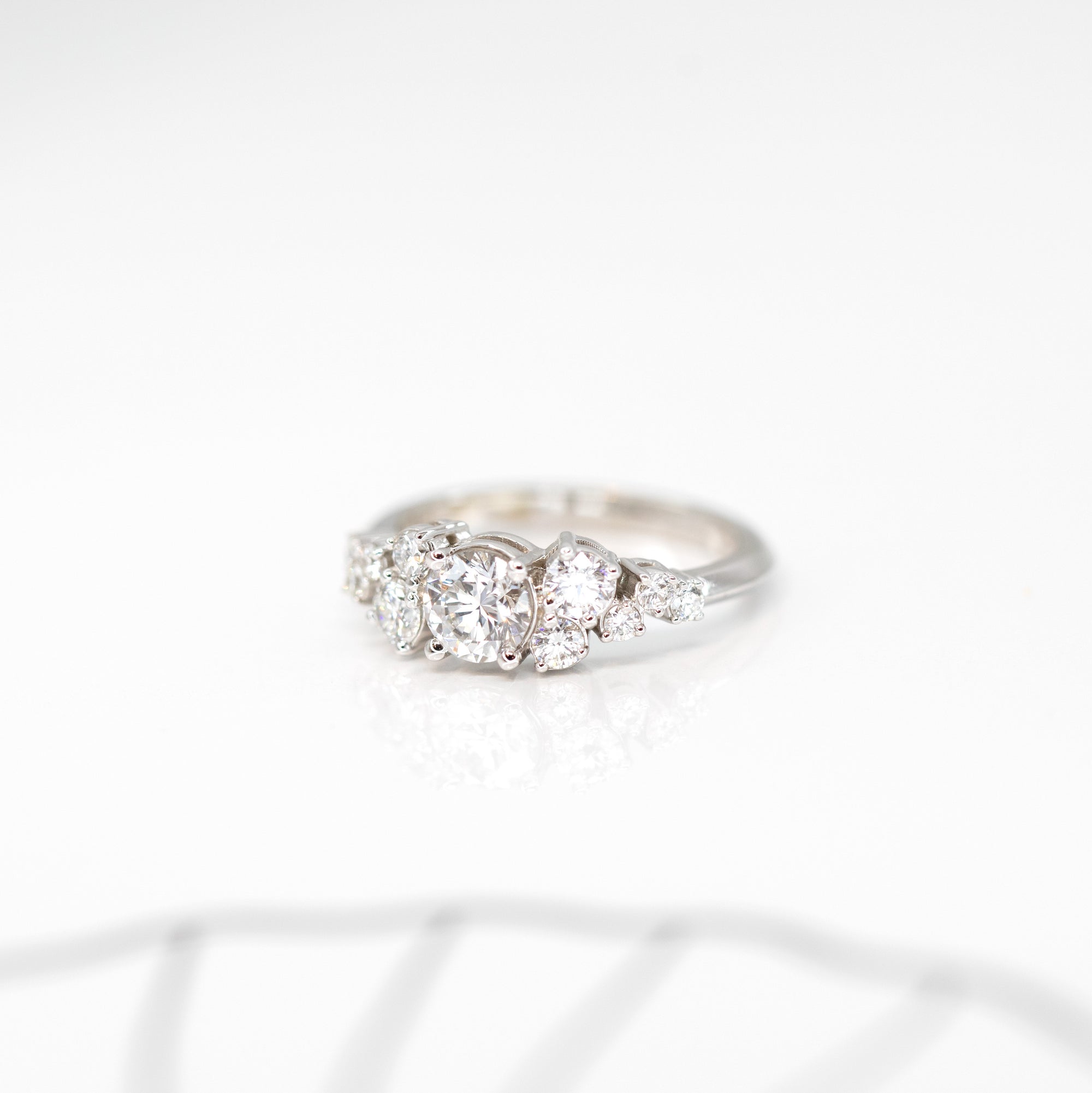 side view of round diamond engagement ring in white gold made whit few extra bright diamonds custom made in montreal by bena jewelry on a white background