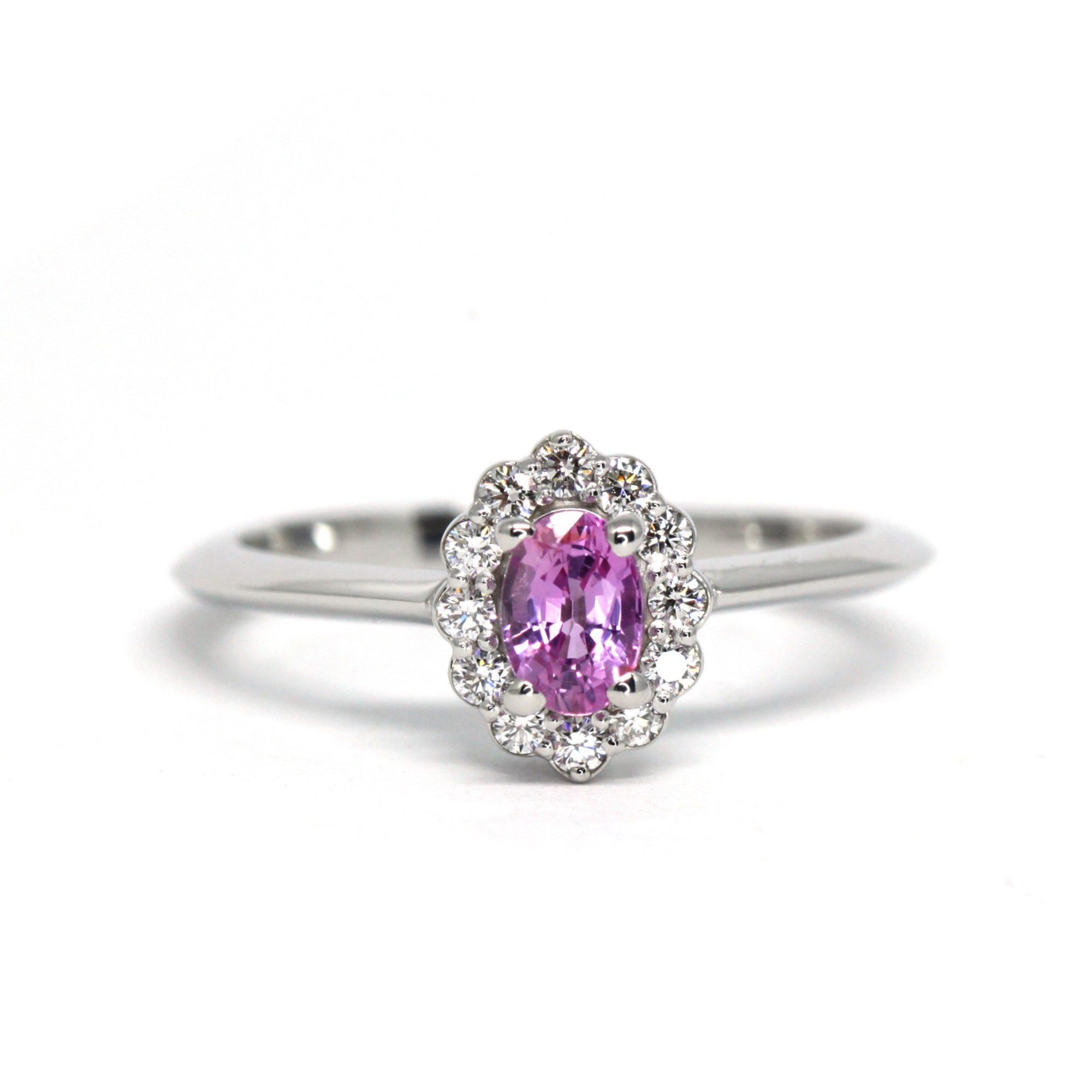 Diamond Halo Pink Sapphire Ring in white gold by Bena Jewelry featuring a pink oval sapphire and diamond halo, photographed on a white background, custom-made in Montreal.