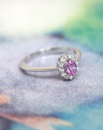 Oval pink sapphire engagement ring with a diamond halo, crafted in white gold by Bena Jewelry, highlighting fine craftsmanship and timeless beauty.