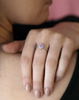 Elegant bridal ring with a pink sapphire and diamond halo, worn on a woman’s hand, highlighting its white gold band, custom-designed by Bena Jewelry in Canada.
