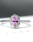 Front view of white gold bridal ring with a diamond halo and pink sapphire, Diamond Halo Ring by Bena Jewelry, displayed on a white background, handmade in Montreal.