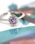 Bridal ring in white gold with an oval pink sapphire and shimmering diamond halo, designed and custom-crafted by Bena Jewelry in Montreal.
