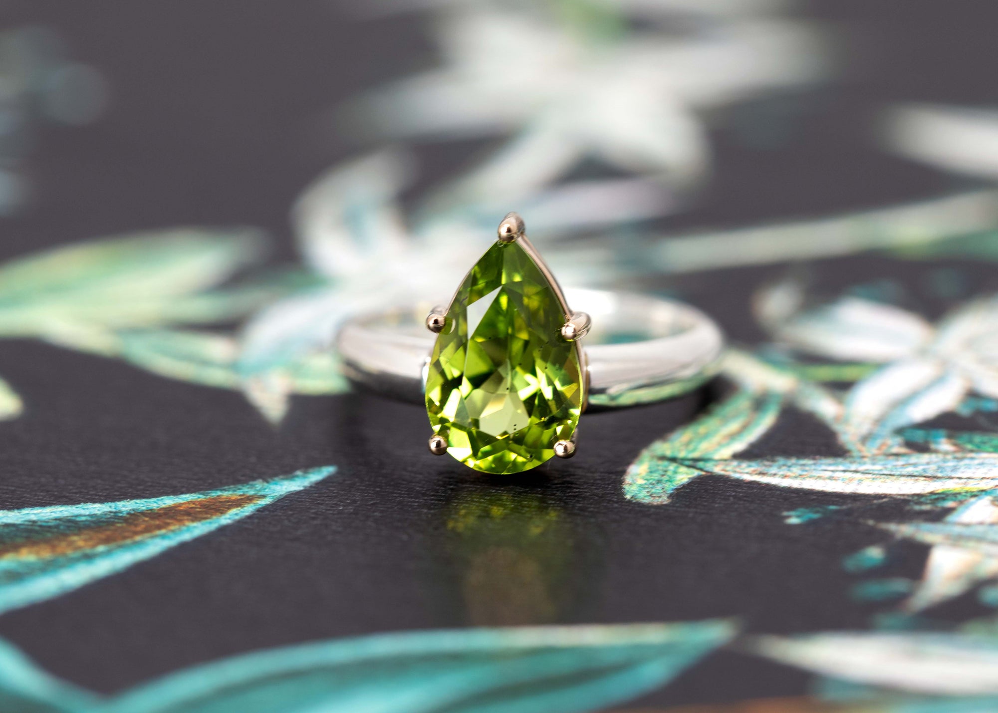 Side angle of peridot ring on white background – The vibrant pear-cut peridot gemstone glows in a sleek, modern setting, handcrafted for a statement look.