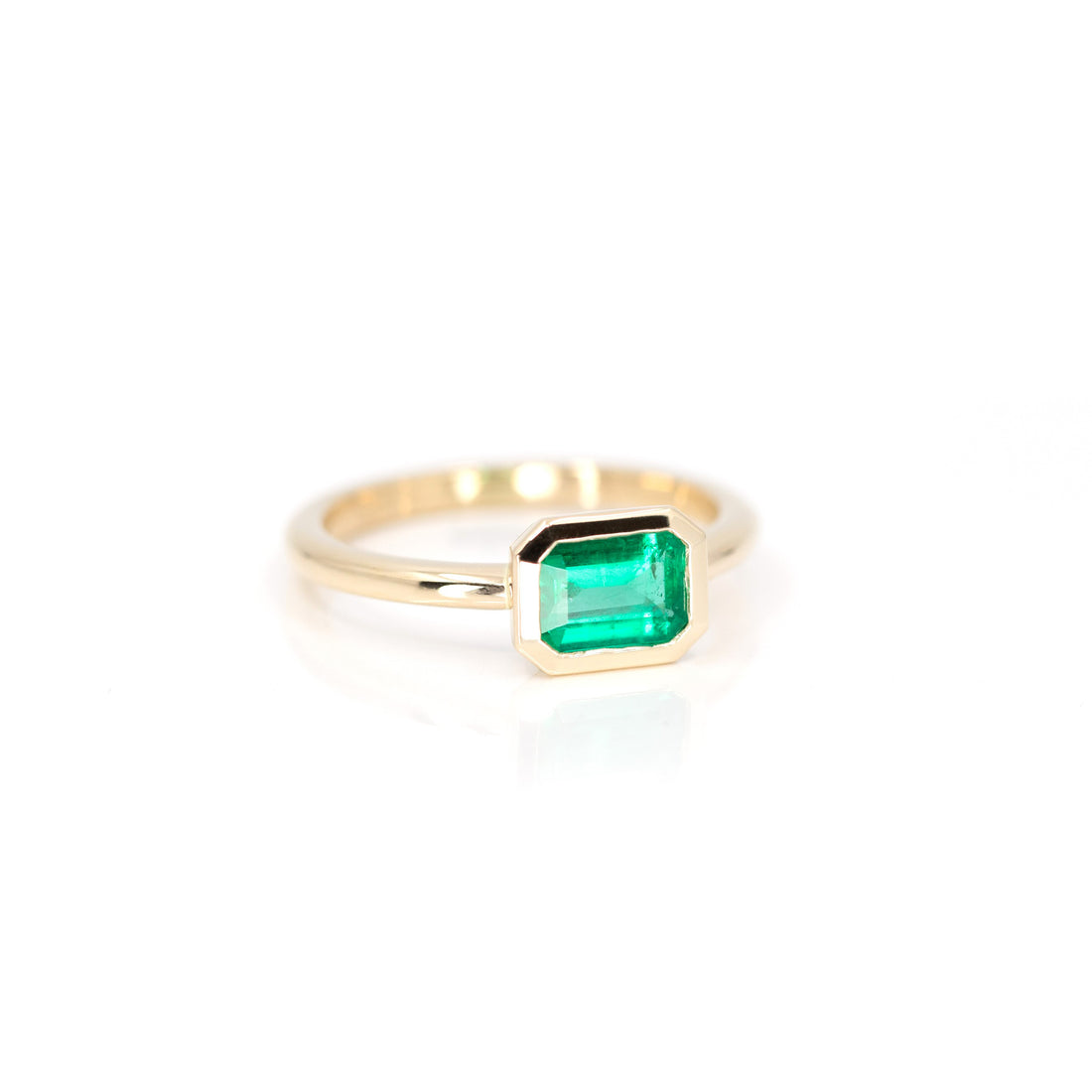 side view of bezel setting emerald gold custom made designer engagement ring in montreal with boutique ruby mardi best jewellery store in montreal on white background