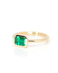 side view of designer bridal engagement ring cusotm made in montreal yellow gold bezel setting emerald ring on white background