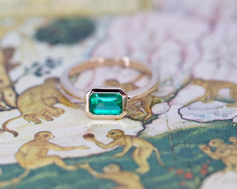 front view of yellow gold emerald bezele setting custom made engagement ring in montreal by bena jewelry designer on multi color background
