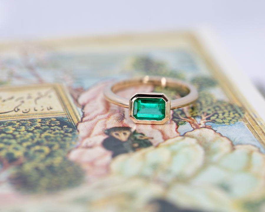 yellow gold emerald engagement ring custom made in montreal designer bena jewelry on multi color background