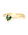 side view of green sapphire yellow gold ring on a white background