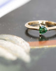 splendid ring with a trillion shaped green gemstone custom made in Montreal on a black background
