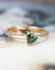 engagement ring with a deep green stone custom made in Montreal on a multicolored background