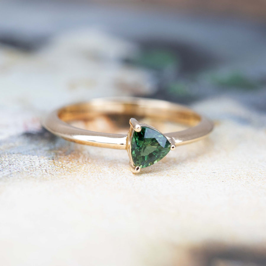 engagement ring with a deep green stone custom made in Montreal on a multicolored background