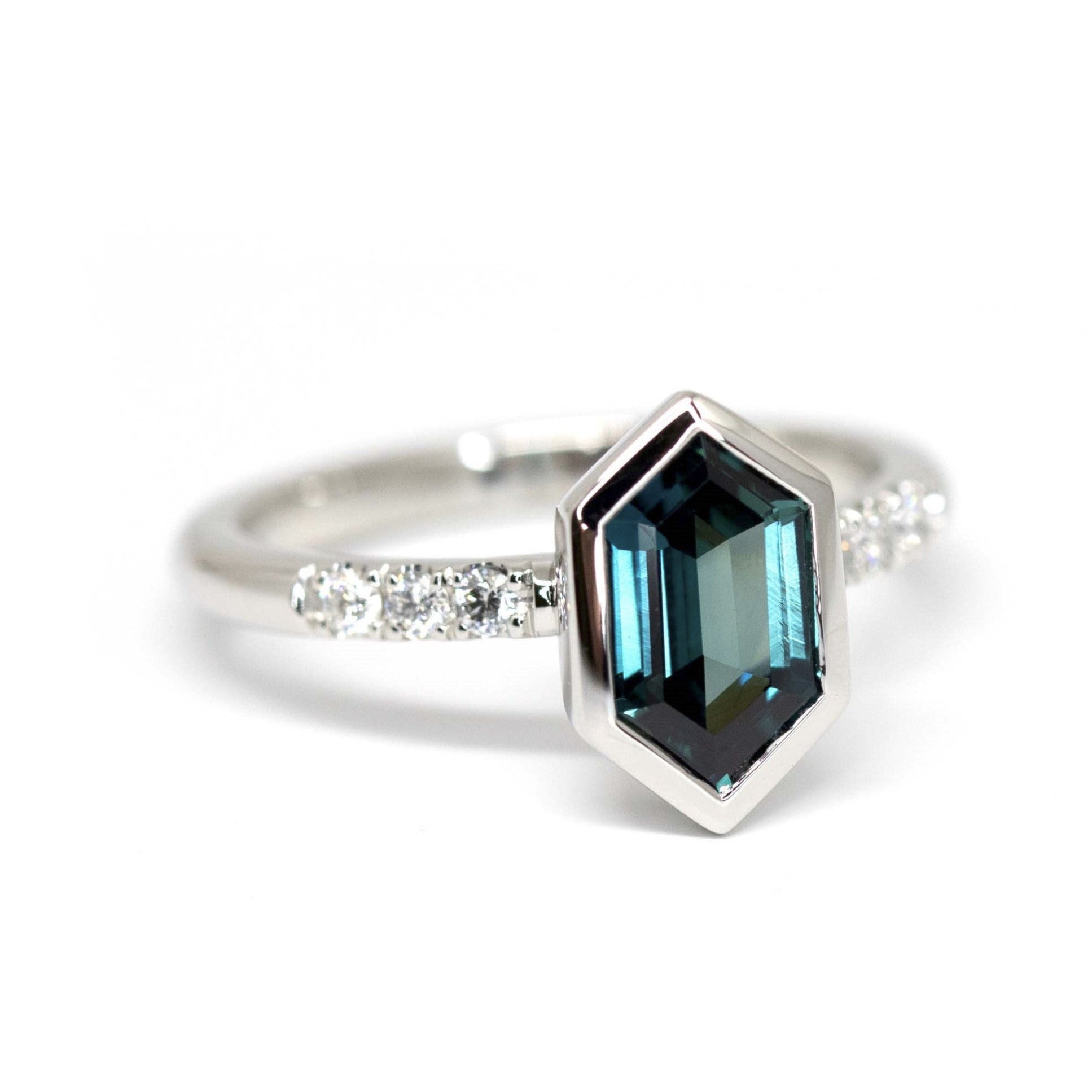Hexagonal Blue Sapphire Platinum Ring on white background – A bold platinum engagement ring featuring a vibrant hexagonal blue sapphire, accented by side diamonds. Designed by Bena Jewelry in Montreal.