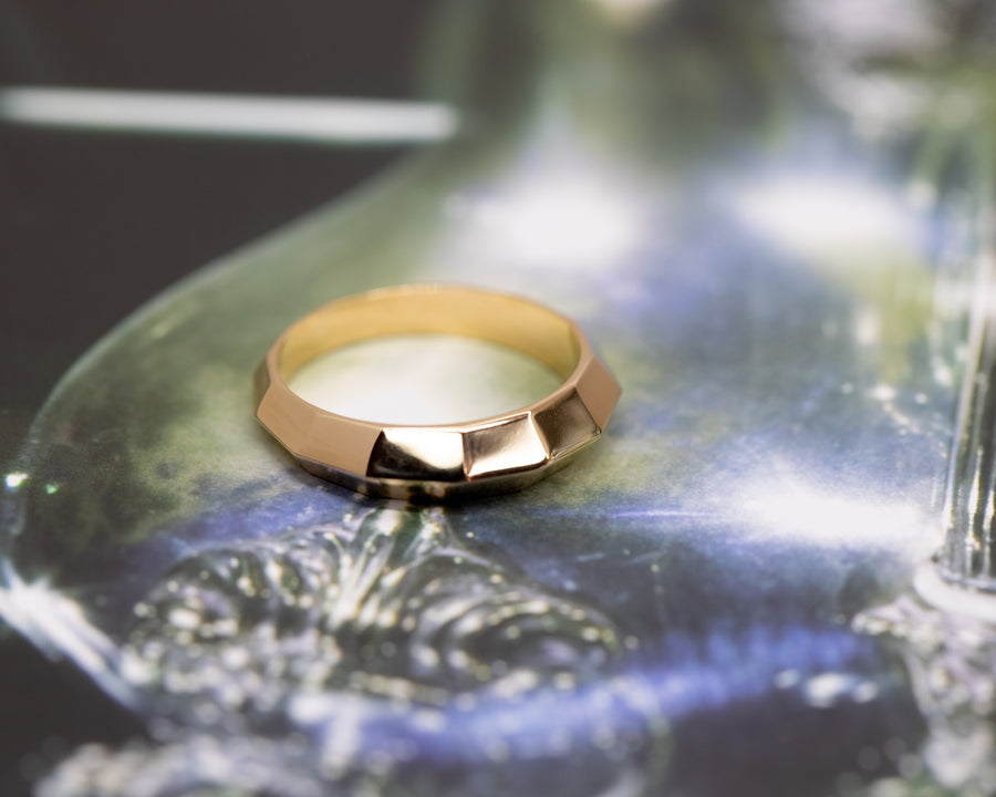 top view of gold ring for men with edgy style from the collection chiseled custom made bridal rings in montreal on dark multi color background