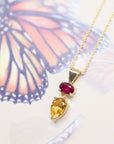 side view of pear citrine and ruby pendant made in yellow gold in montreal by bena jewelry designer on a multi color background