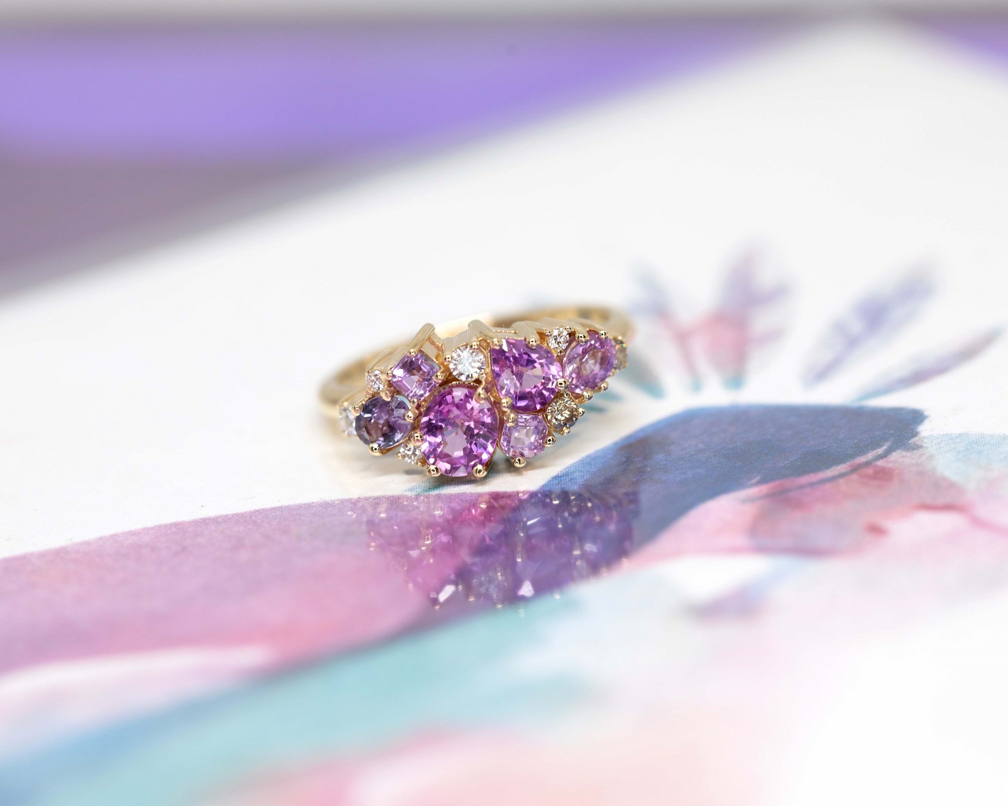 Highlights the interplay of pink and violet gemstones with the polished yellow gold band. Custom jewelry by Bena Jewelry, Montreal, Canada.