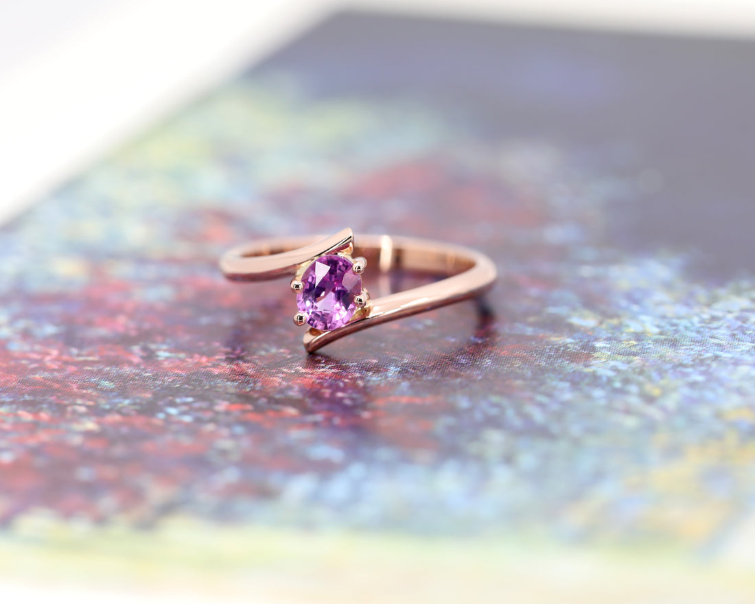 front view of oval shape pink sapphire rose gold engagement ring minimalist twist band edgy bridal style on multi color background