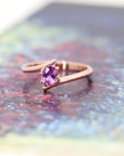 front view of oval shape pink sapphire rose gold engagement ring minimalist twist band edgy bridal style on multi color background