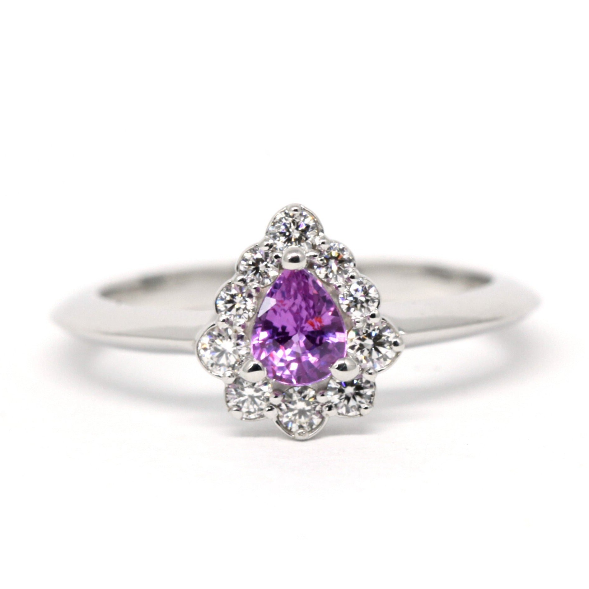 Custom-made bridal ring in white gold, featuring a mesmerizing pink-violet sapphire and diamond halo. Designed and handcrafted in Montreal by Bena Jewelry, a Canadian jewelry designer.