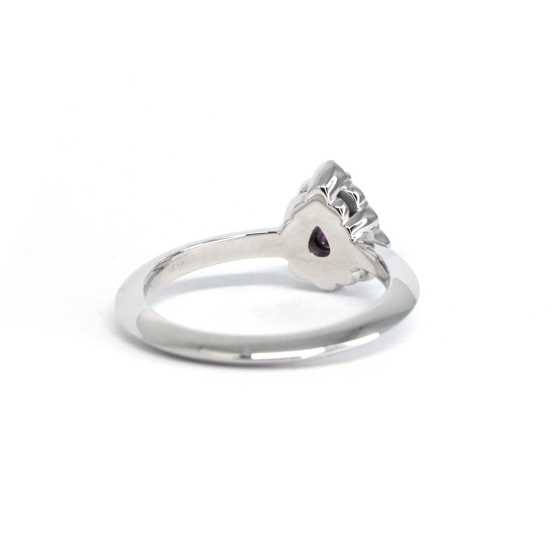 Top-down perspective of the Aura engagement ring, featuring a luminous pear-shaped pink-violet sapphire in a halo of sparkling diamonds. Handmade by Bena Jewelry, designer in Montreal, Canada.