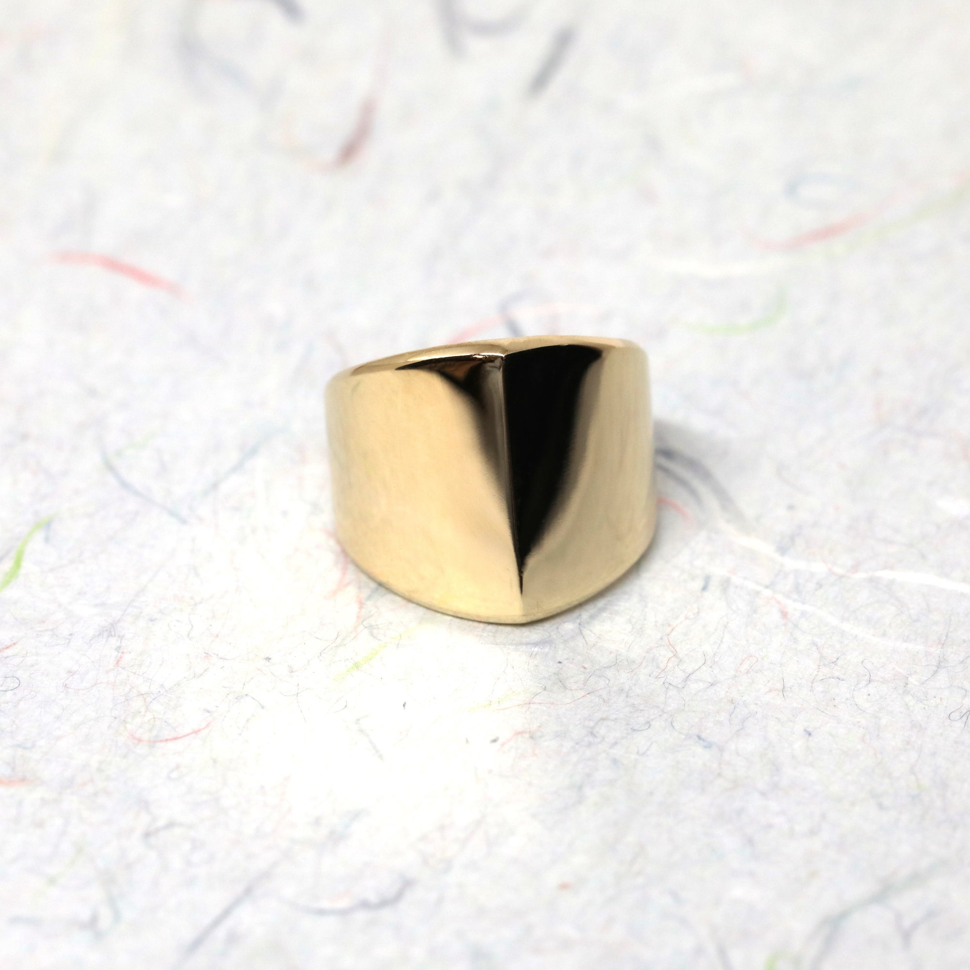 Close-up of gold ring on dark background – The bold structure of the boxy ring stands out against the dark backdrop, highlighting its modern elegance.