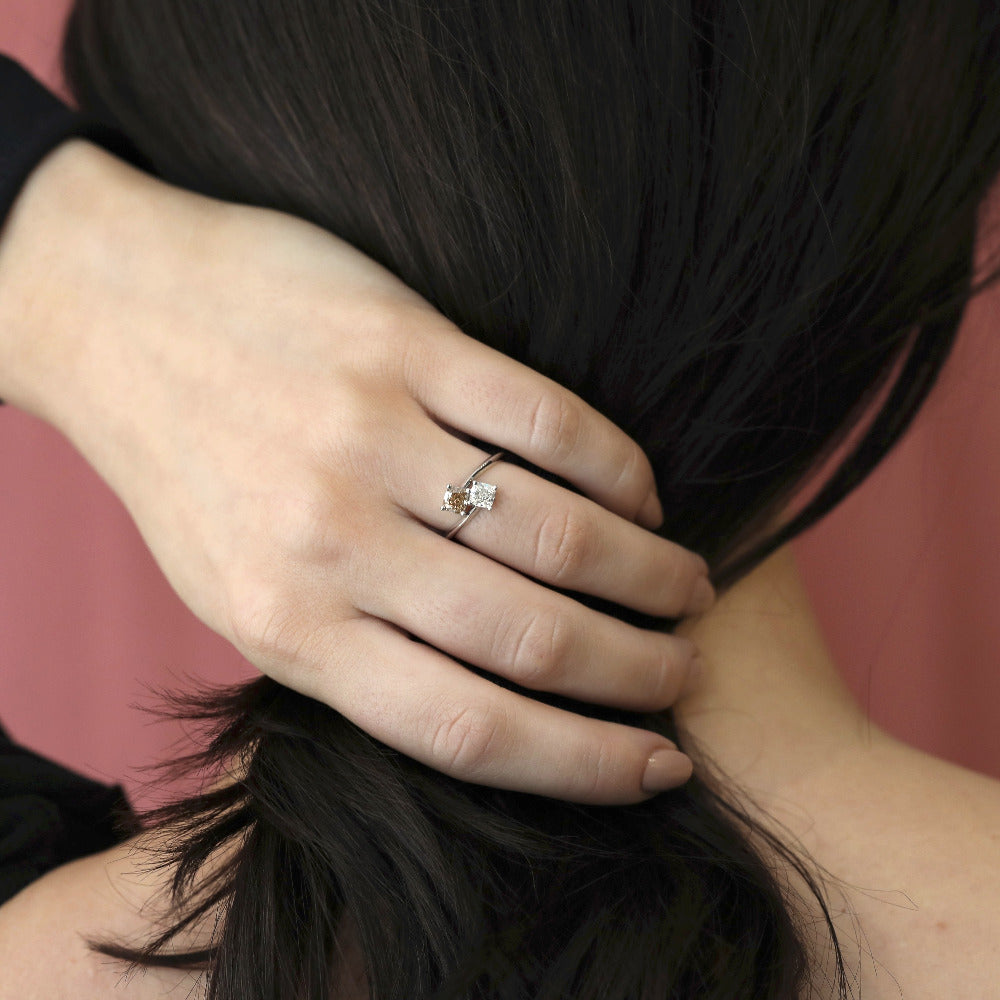 Double Cushion Diamond Ring worn on hand, close-up – A refined Toi et Moi engagement ring featuring a white and brown cushion-cut diamond in white gold. Handmade by Bena Jewelry in Montreal.
