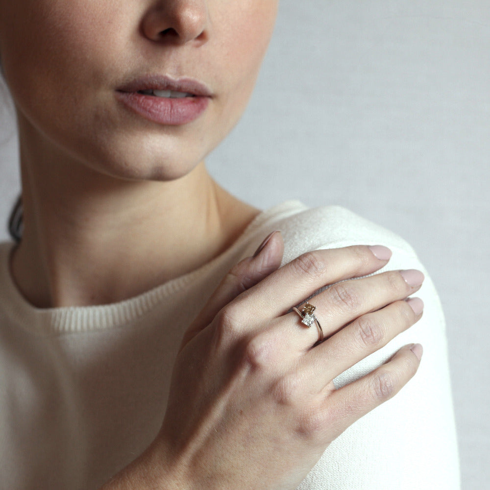Toi et Moi ring on soft-toned background – The warm brown diamond and brilliant white diamond create a striking contrast.