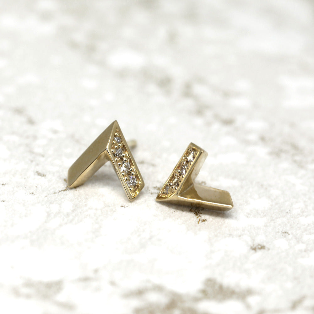 An angled shot of the Arrow Diamond Studs, Edition 2 by Bena Jewelry, capturing the modern arrow design, sparkling diamonds, and bold craftsmanship in yellow gold, made in Montréal, Canada.