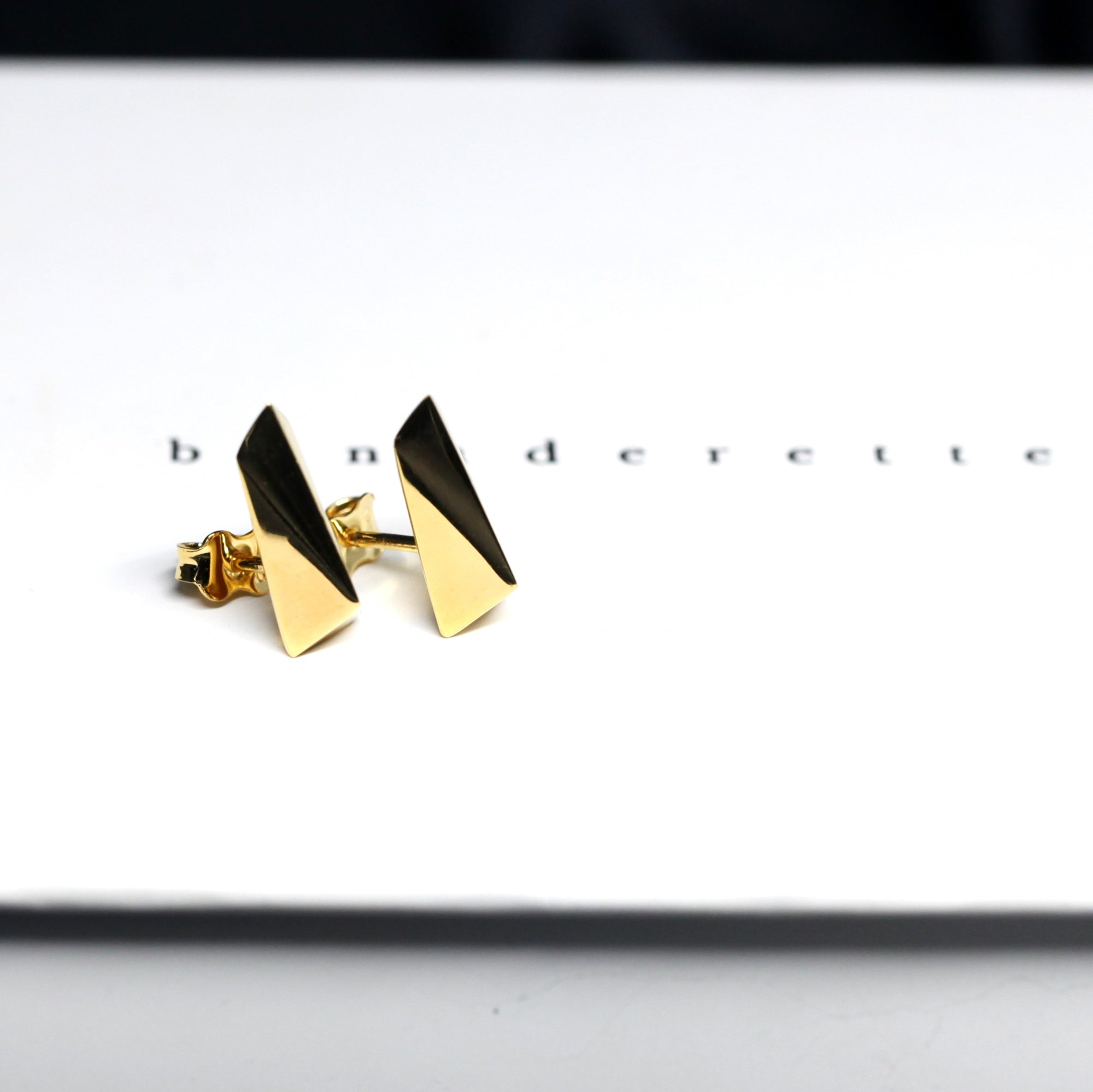 Top-down view of gold earrings – Sleek, edgy earrings with a clean, architectural shape. A signature design from Bena Jewelry, made in Canada.