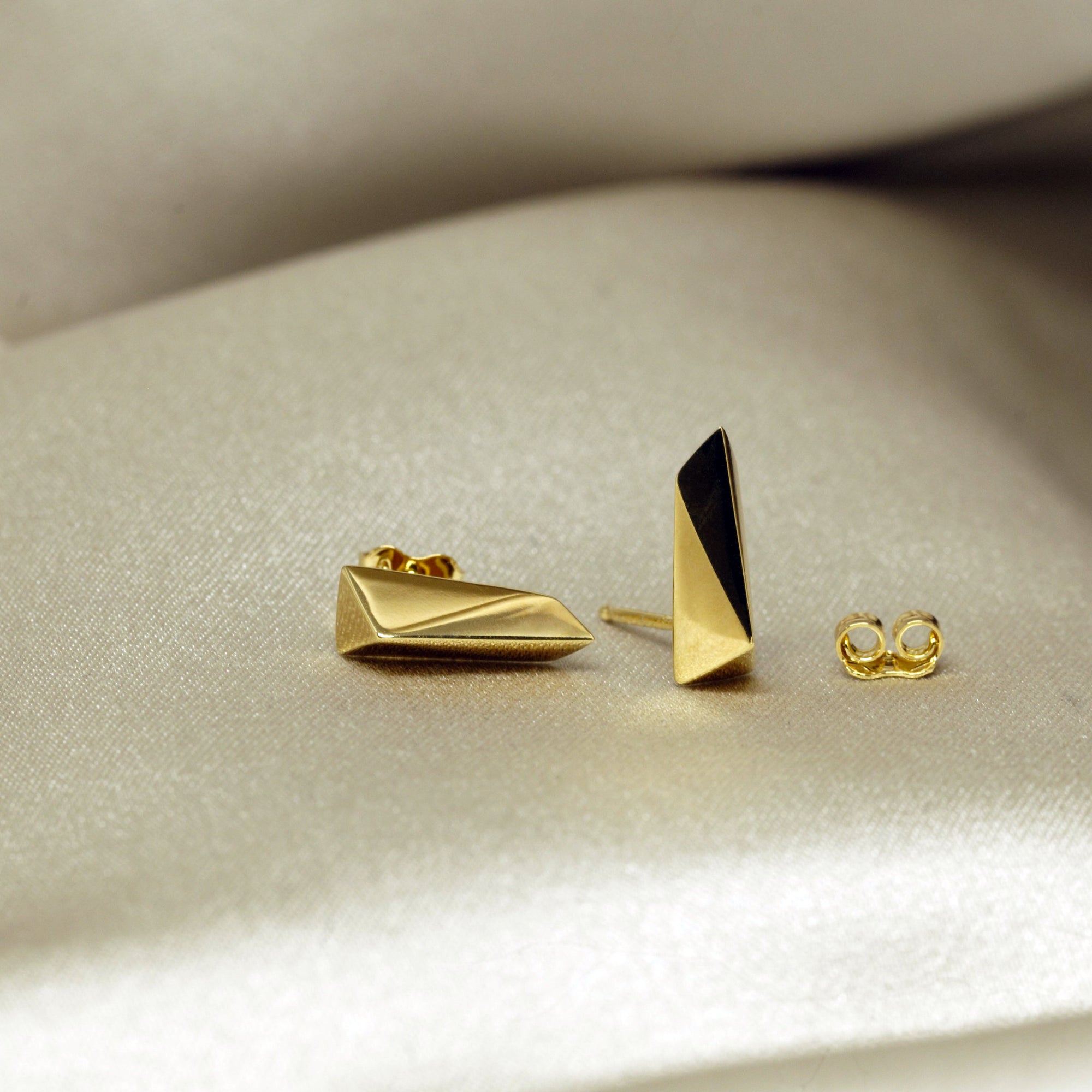 Close-up of gold earrings on dark background – Striking statement earrings in gold with a refined, contemporary aesthetic. A unique creation by Bena Jewelry, Montreal.